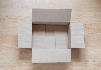 Top view from above of open empty brown cardboard box on wooden background. Paper corrugated can use recycle. Mockup design, carton box product for packaging shipping and storage in the warehouse.