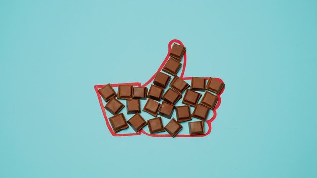 Square Pieces Of Chocolate Fill The Hand Sign "Like" On Blue Background.