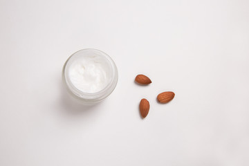 Top view of the jar with a natural, organic cream for face and body. Next to some almond.