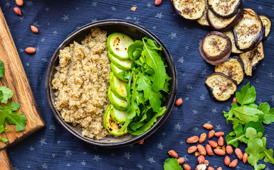 Quinoa amaranth grain cereal cooked porridge with zucchini vegetables and rucola leaves in bowl. Vegan balanced healthy food.