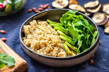 Quinoa amaranth grain cereal cooked porridge with zucchini vegetables and rucola leaves in bowl. Vegan balanced healthy food.