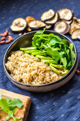 Quinoa amaranth grain cereal cooked porridge with zucchini vegetables and rucola leaves in bowl. Vegan balanced healthy food.