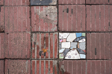 Sidewalk tile replaced by broken pieces of different colored tiles