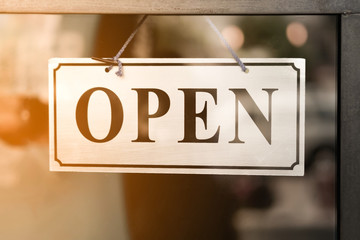 A business sign that says open on cafe or restaurant hang on door at entrance.