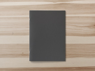 Black cover Magazine or Brochure on brown wooden background. Front cover top view. Template concept for your showcase.
