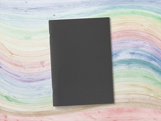 Black cover Magazine or Brochure on colors wooden background. Front cover top view. Template concept for your showcase.