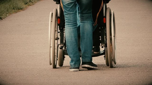A disabled person who is pushed in a wheelchair by a family member on a walk in the Park