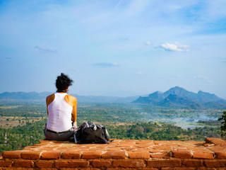 young woman sitting on the top of the world heritage Sigiriya Rock