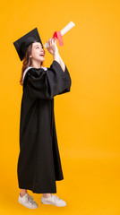 happy young woman in graduation gowns and looking through the diploma