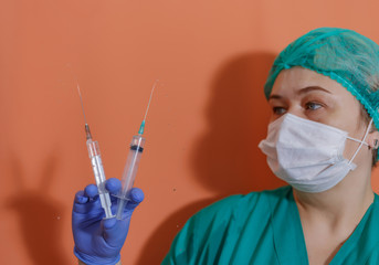 A doctor wearing a protective mask and gloves shows a syringe with a vaccine to work with the...