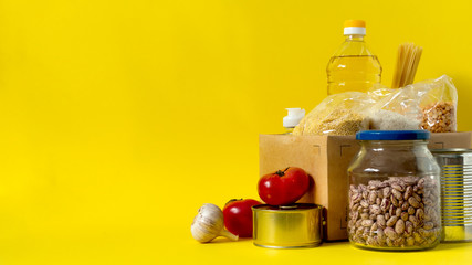 Fototapeta na wymiar Banner.Donation. Food supplies crisis food stock for quarantine isolation period on yellow background. Rice, peas, cereals, canned food, oil, vegetables, mask, sanitizer. Food delivery. Cope space.