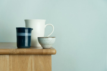 white ceramic mug and tea cup on nature wood table with vintage blue wall for food drink and interior background