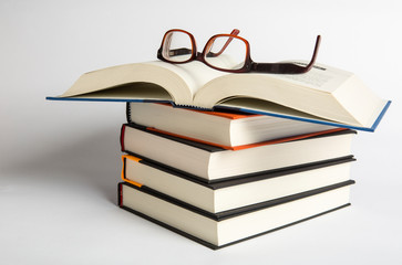 Stacks of hardback books with reading glasses. Reading concept. copy space. A collection of books read