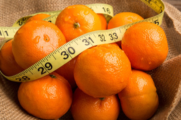 Nutrition Weight loss concept, Bright Healthy organic orange fruit in burlap with tape measure for weight loss and fiber. Boost immune system