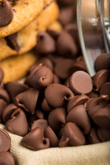 Delicious and tempting Pile of Dark chocolate chips morsels and chocolate chip cookie close up in a glass jar