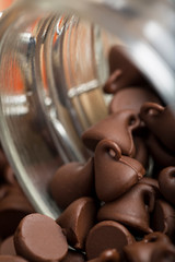 Macro photography .Delicious and tempting Pile of Dark chocolate chips morsels and chocolate chip cookie close up in a glass jar