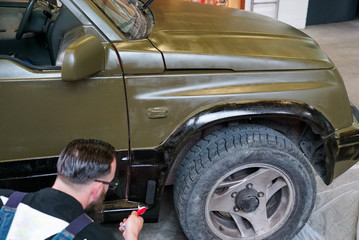 close up of a man painting an army jeep and adding black trim