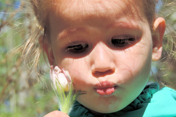 The girl`s face pouted a flower a snowdrop Bud against her cheek sad look