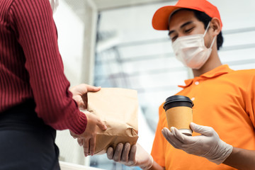Obraz premium Asian deliver man wearing face mask in orange uniform handling bag of food and hot coffee give to woman costumer in front of the house. Postman and express grocery delivery service during covid19.