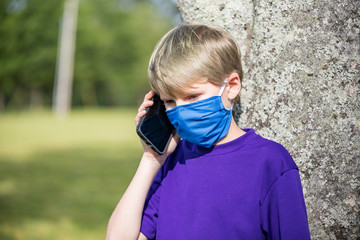 A child talks on cell phone while wearing a face mask during the coronavirus pandemic