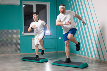 Fat man is very hardworking doing step-up exercises on steps during group fitness classes. Excess weight
