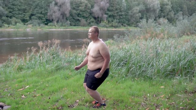 Fat guy jumping on the background of the river.