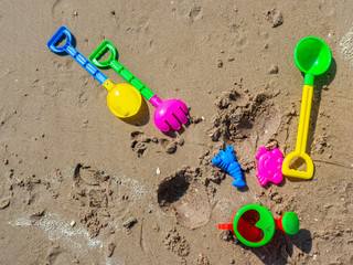 Fototapeta na wymiar Colorful children's beach toys on sand background.