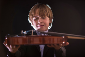 Fototapeta na wymiar boy hugging his violin, in an attitude of love for music Boy shows his violin to the camera