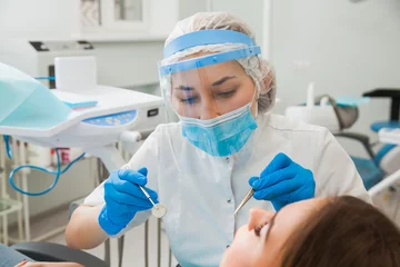 Keuken foto achterwand Tandarts Jonge vrouwelijke tandarts die de tanden van de patiënt geneest en de holte vult