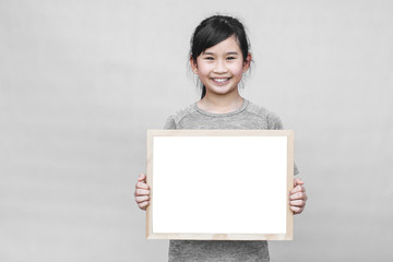Little asian girl holding whiteboard isolated on gray background.