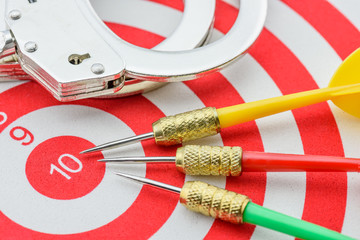 Three darts with a handcuff on a dartboard, depicting the heart of misconduct is the difficult...