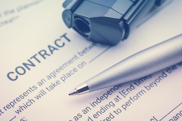 Pen and a gun or a pistol on a legal contract form