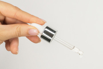 Glass pipette serum or oil essence dropper . Skincare beauty product in hand on the white background. wellness and self care. Natural organic cosmetic. Close-up oil face drop. Copy space for salon