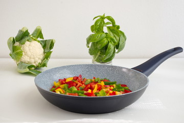 Frying pan and colorful vegetables on white background