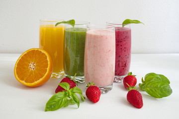 Colorful smoothies in glass with fresh fruits on white table
