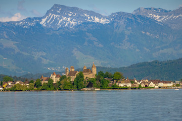 Fototapeta premium View of old city of Rapperswil dominated by its 13th century castle and the alps in the background, St. Gallen, Switzerland