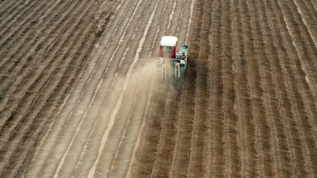 Cinematic aerial drone shots of a flax machine going fast through the field