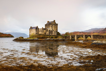 Eilean Donan Castle during colourful sunrise - Dornie, Scotland - United Kingdom. Mountains with snow in background.