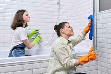 Mother and teenager daughter cleaning together in bathroom