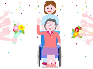 車いすの高齢者に祝いの花束を贈る。