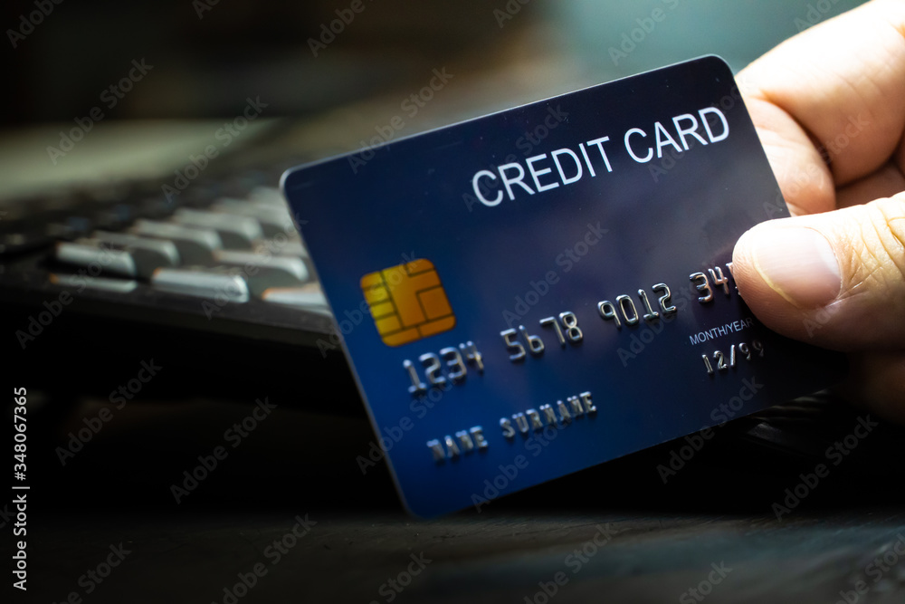 Poster close up Shallow focus hand hold Credit Card on Computer keyboard. Background for E-commerce and online shopping concept.