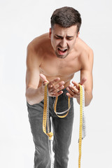 Sick man with measuring tapes on color background. Concept of anorexia