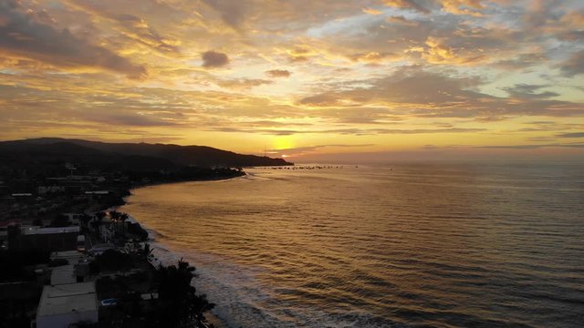 Gorgeous orange sunset by the beach of surf town Mancora, aerial shot in Peru