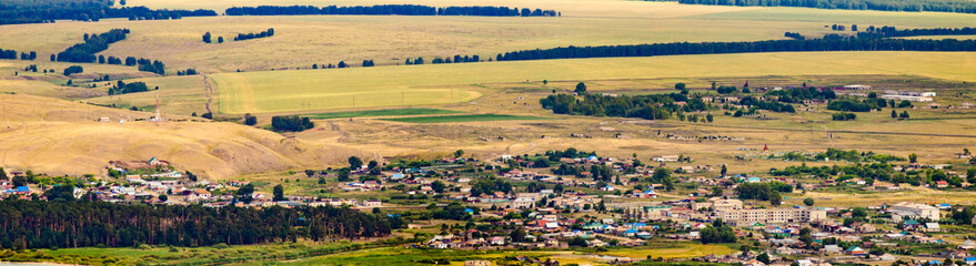 Obraz premium village in the mountains aerial view among fields and mountains and clouds by the lake