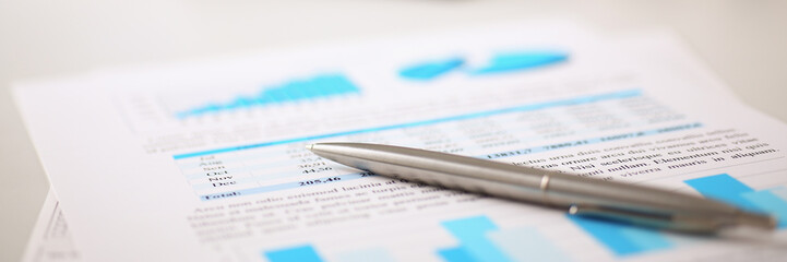 Financial statistics documents on clipboard pad at office table closeup