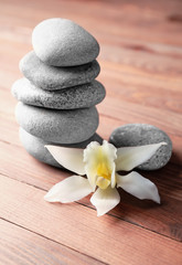 Stack of spa stones and flower on wooden background