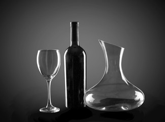 Bottle of wine, glass and decanter on dark background