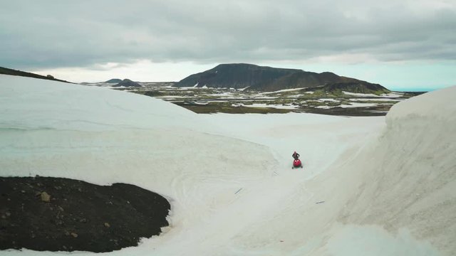 Solitary Male Riding Snowmobile on Snow Capped Valley in Highlands of Iceland