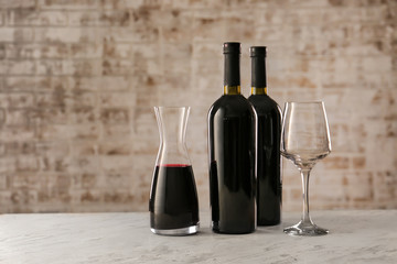 Decanter, bottles of wine and glass on table