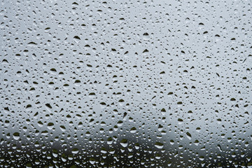 Rain drops on glass window. Dark grey textured background. Full frame macro photo. 